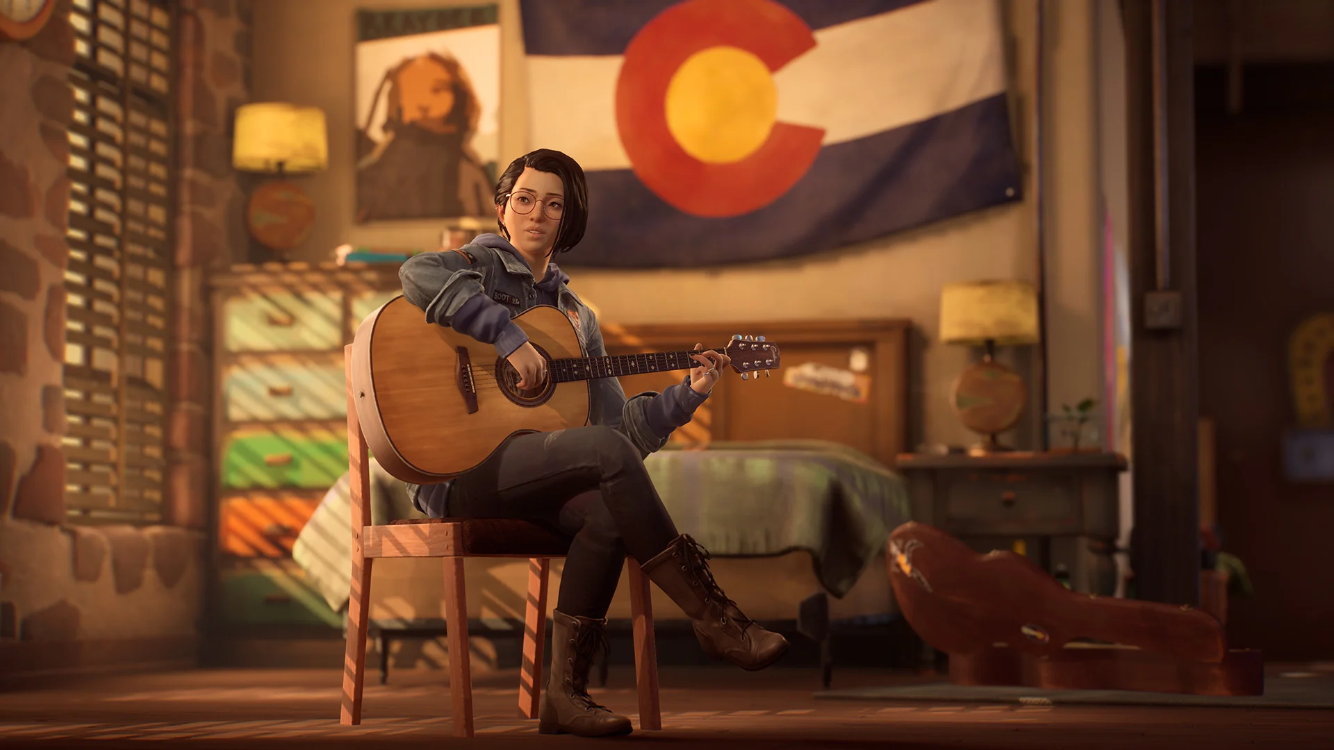 A person with a guitar in a bedroom under a Colorado flag.