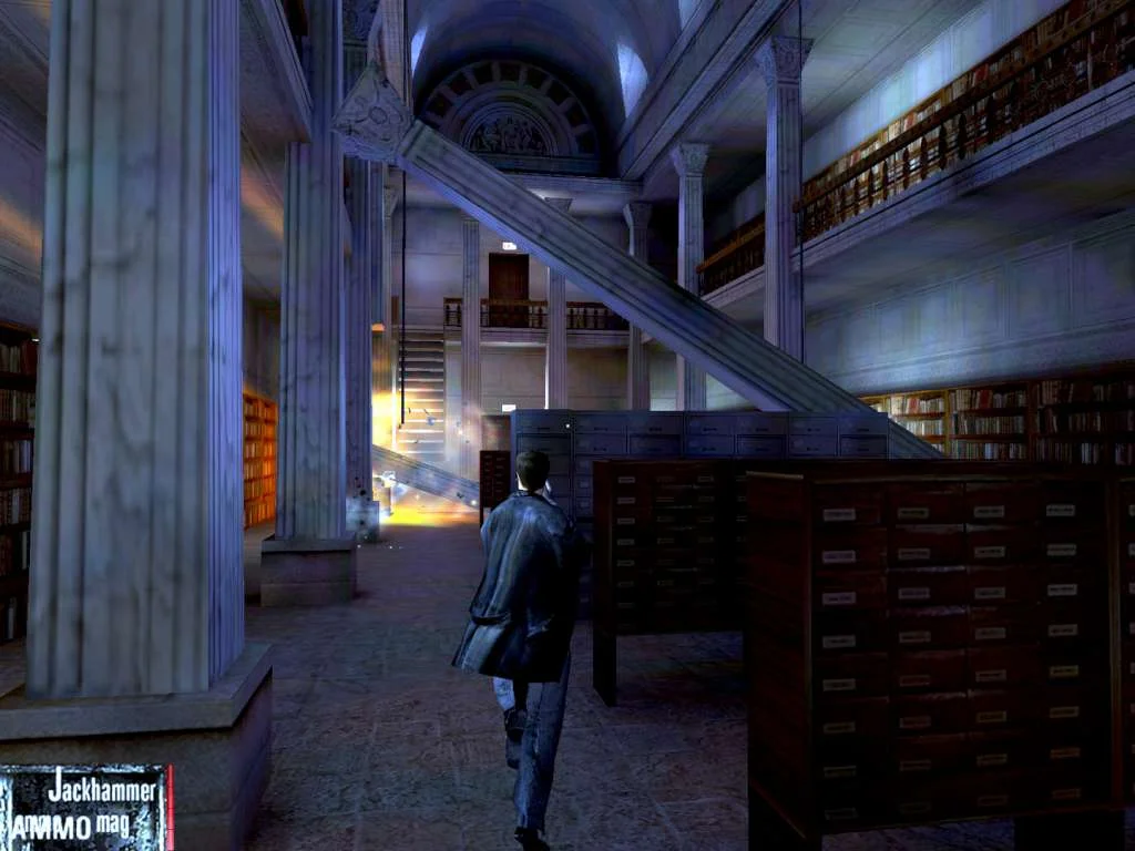 Max Payne walks a columned library hall past wooden card catalogs with Jackhammer ammo on screen