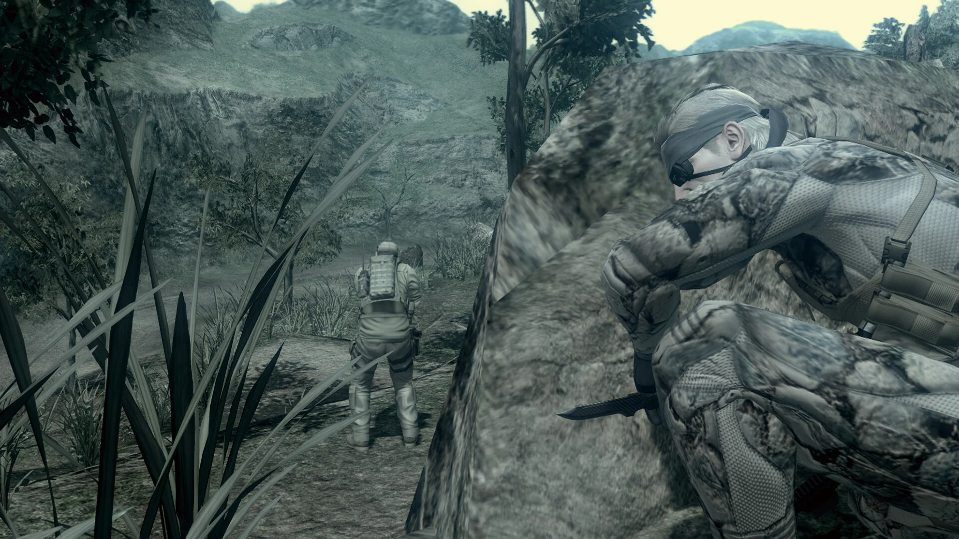 Camouflaged Snake with a knife behind a rock while a soldier stands on a jungle path
