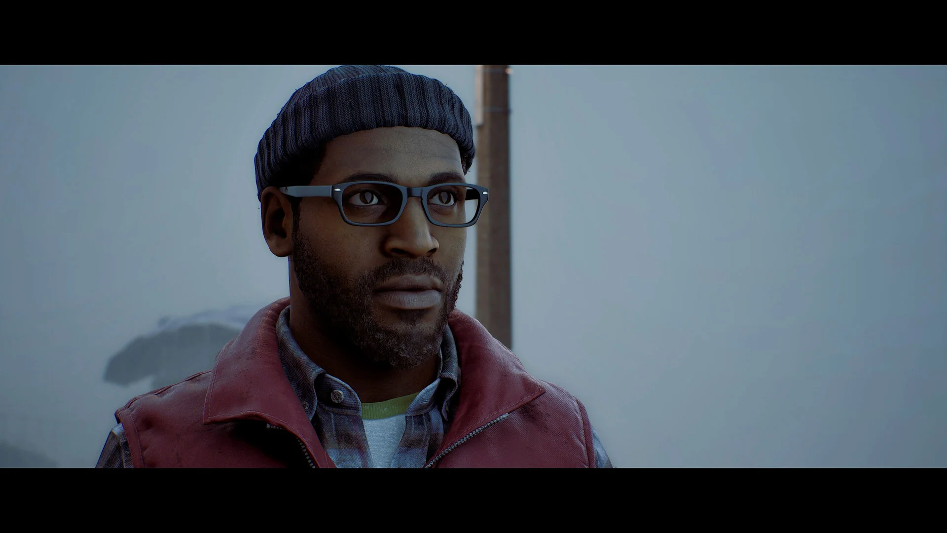 Close view of Simon Ordell in a beanie and glasses, red vest, against grey fog