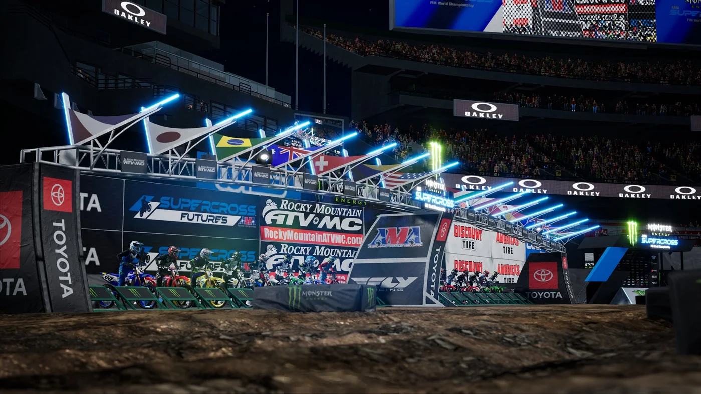 Riders waiting in a lit starting gate under Japan Brazil UK and Swiss flags