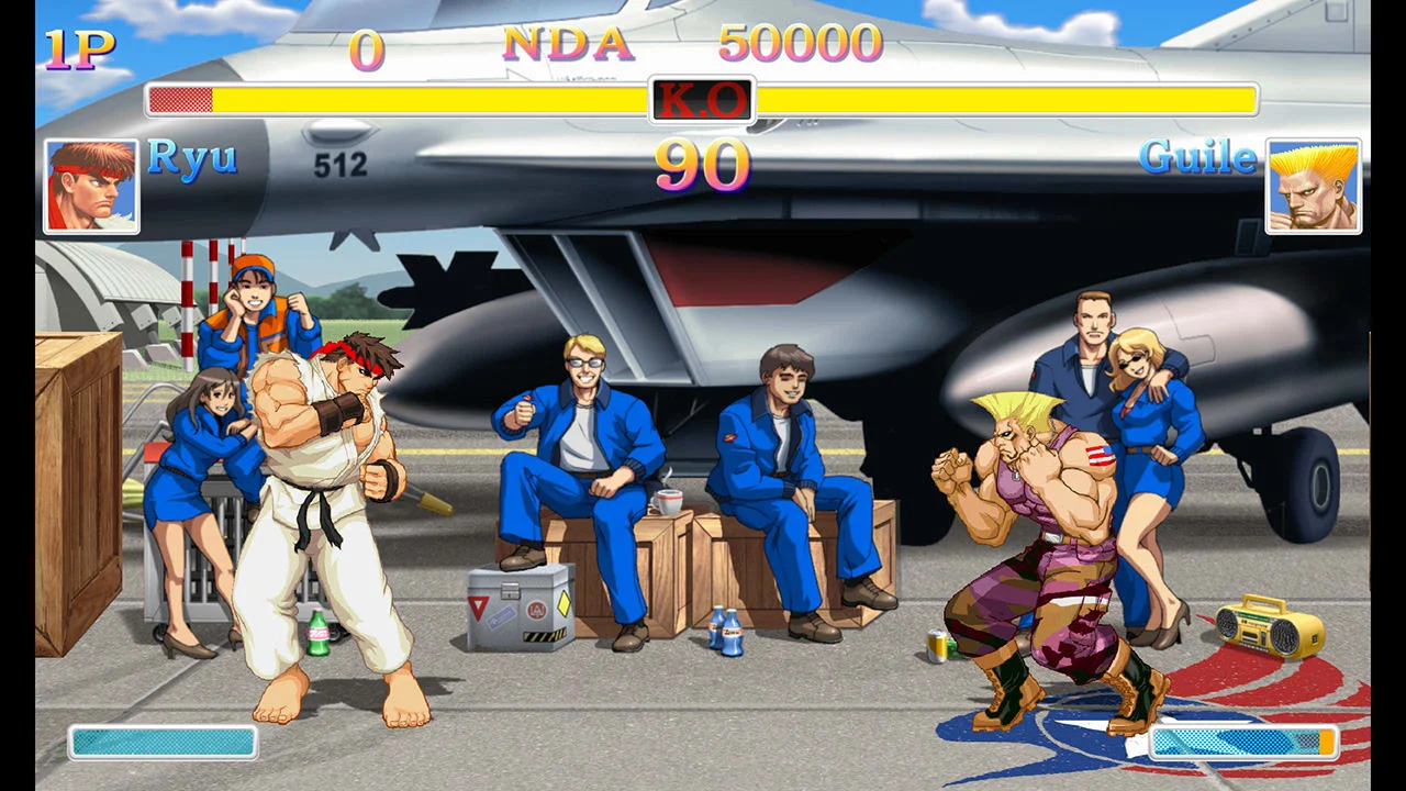Chun-Li and Guile stand in an airport lounge with other fighters seated behind them.