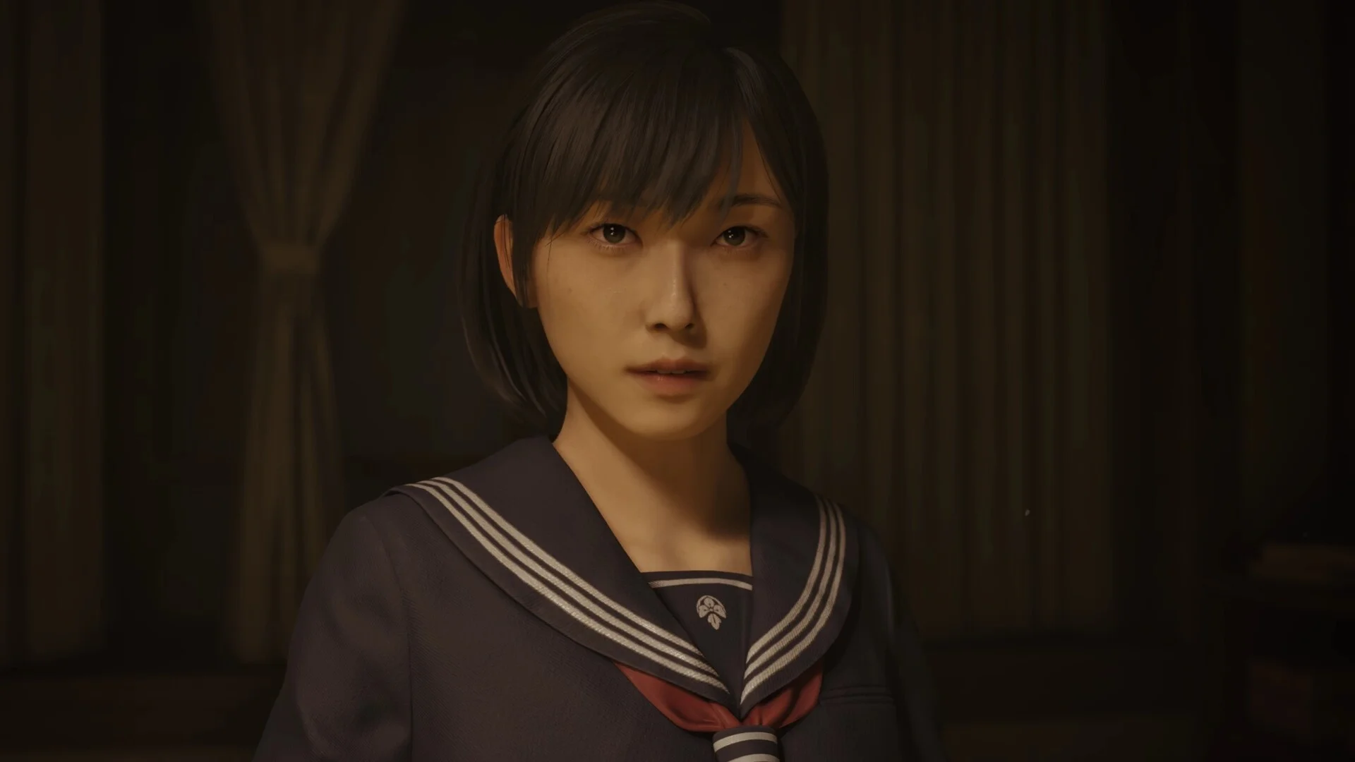 Close portrait of Hinako in a navy sailor uniform with a red tie in a dark room