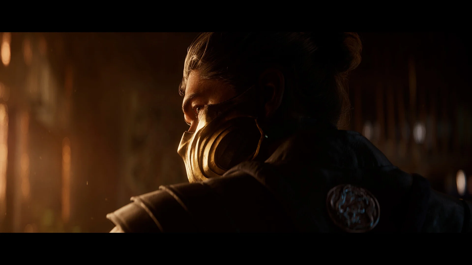 Side profile of a man with a gold mask and topknot in warm lantern light