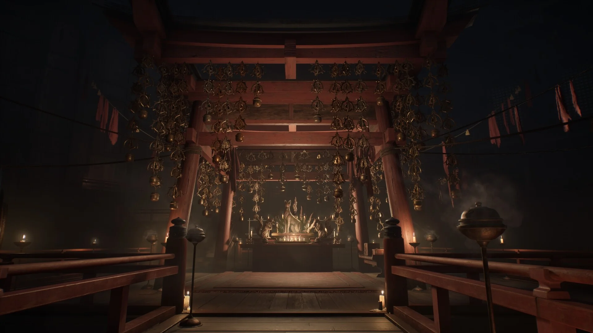 A red shrine hall with hanging bells and a fox statue altar lit by candles