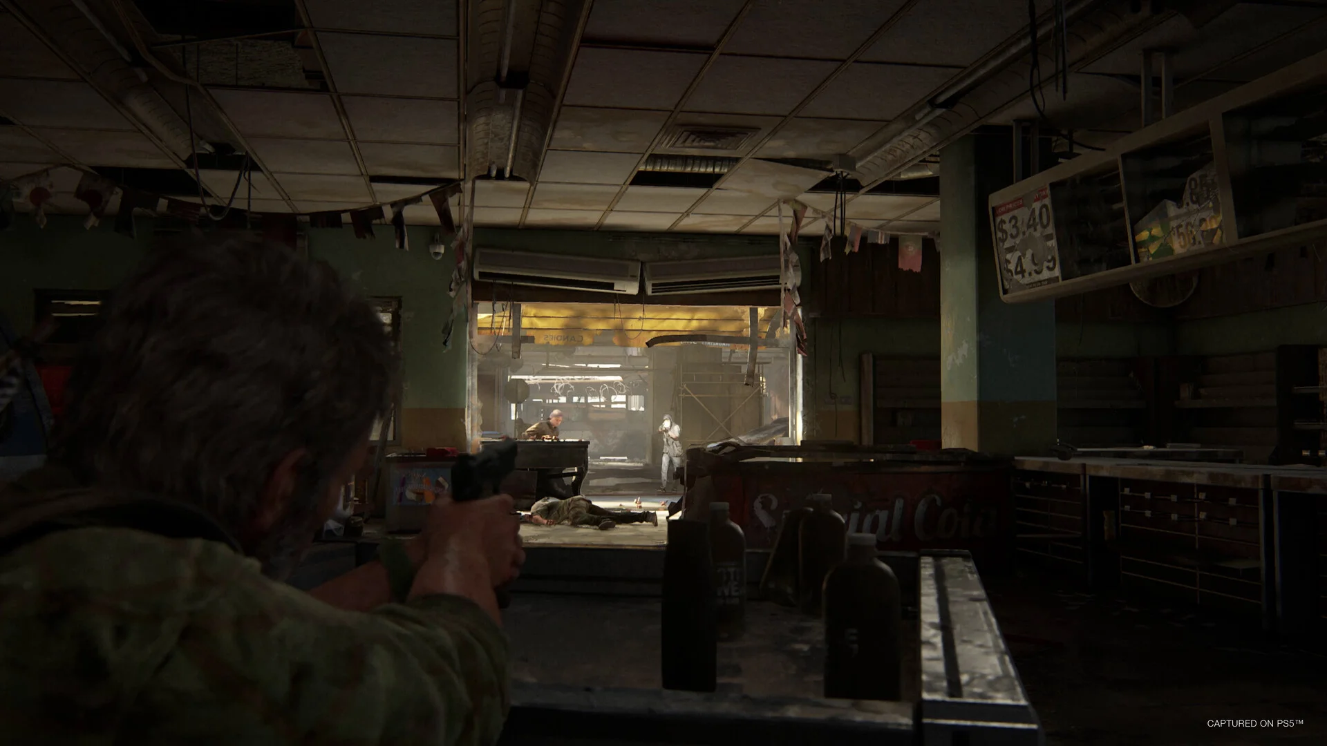 Joel aims a handgun across a ruined shop counter toward two armed figures in the doorway