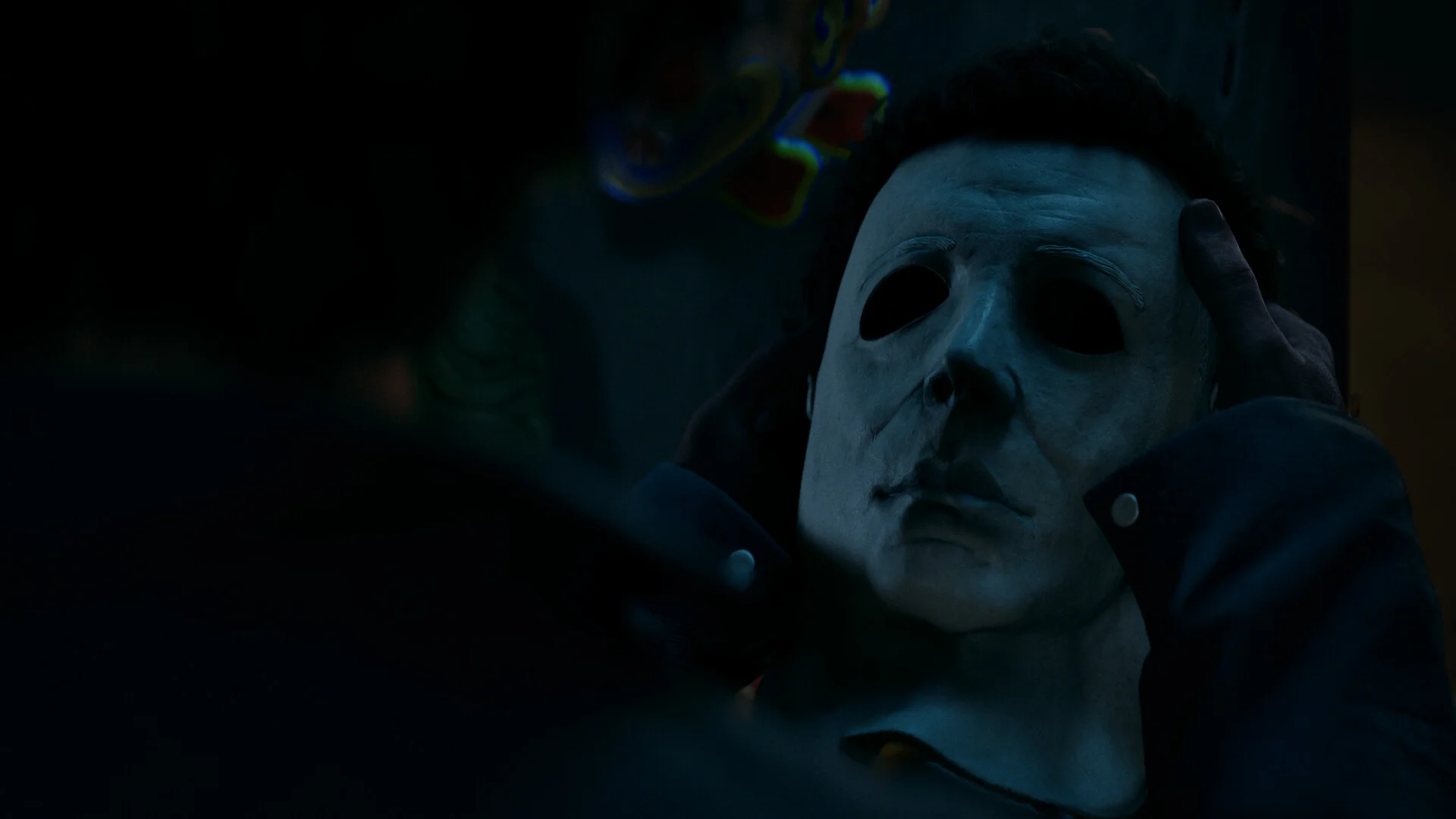 Close-up of Michael Myers white mask being held in both hands in a dark room