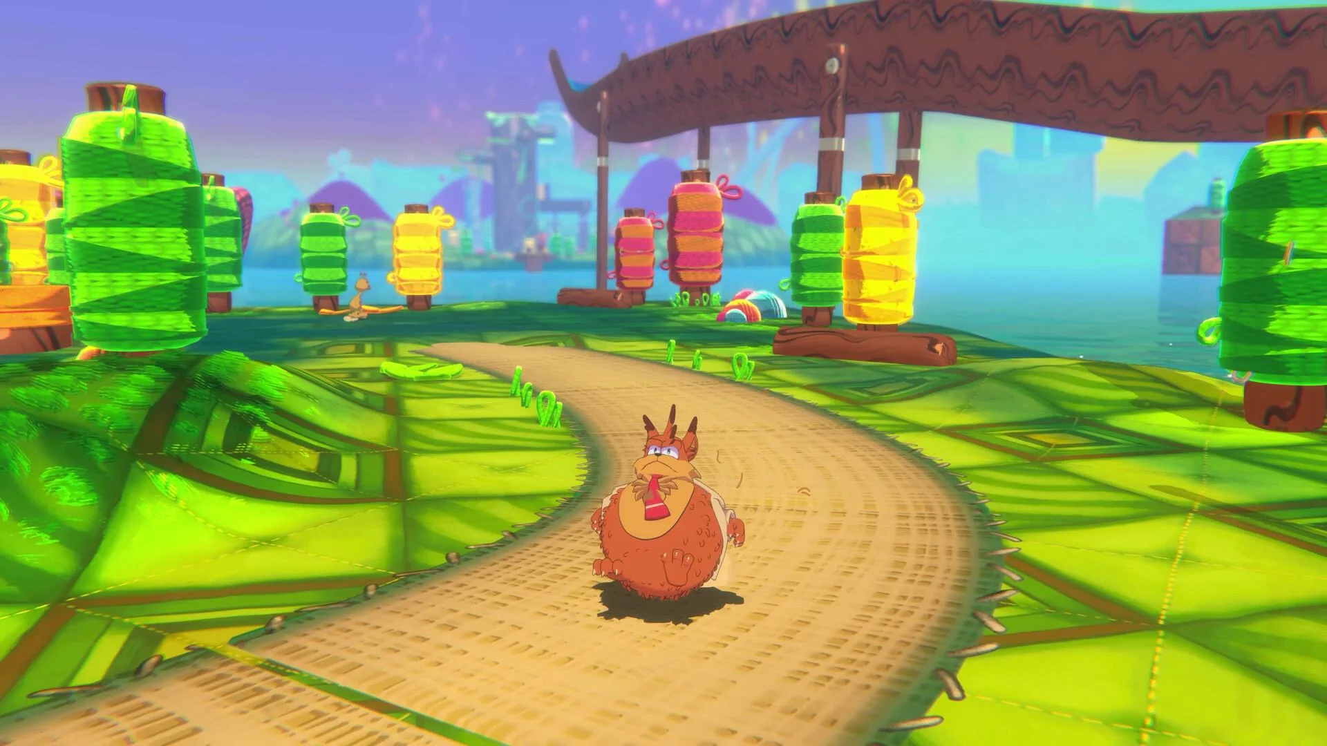 Hairball bobcat rolling a sand path among giant green yellow pink yarn-spool lanterns on a leaf-stitch island