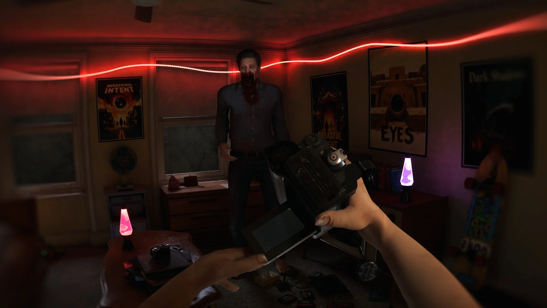 First-person camcorder aimed at a man with a bloody mouth, red LED strip across the room, posters and a lava lamp behind him