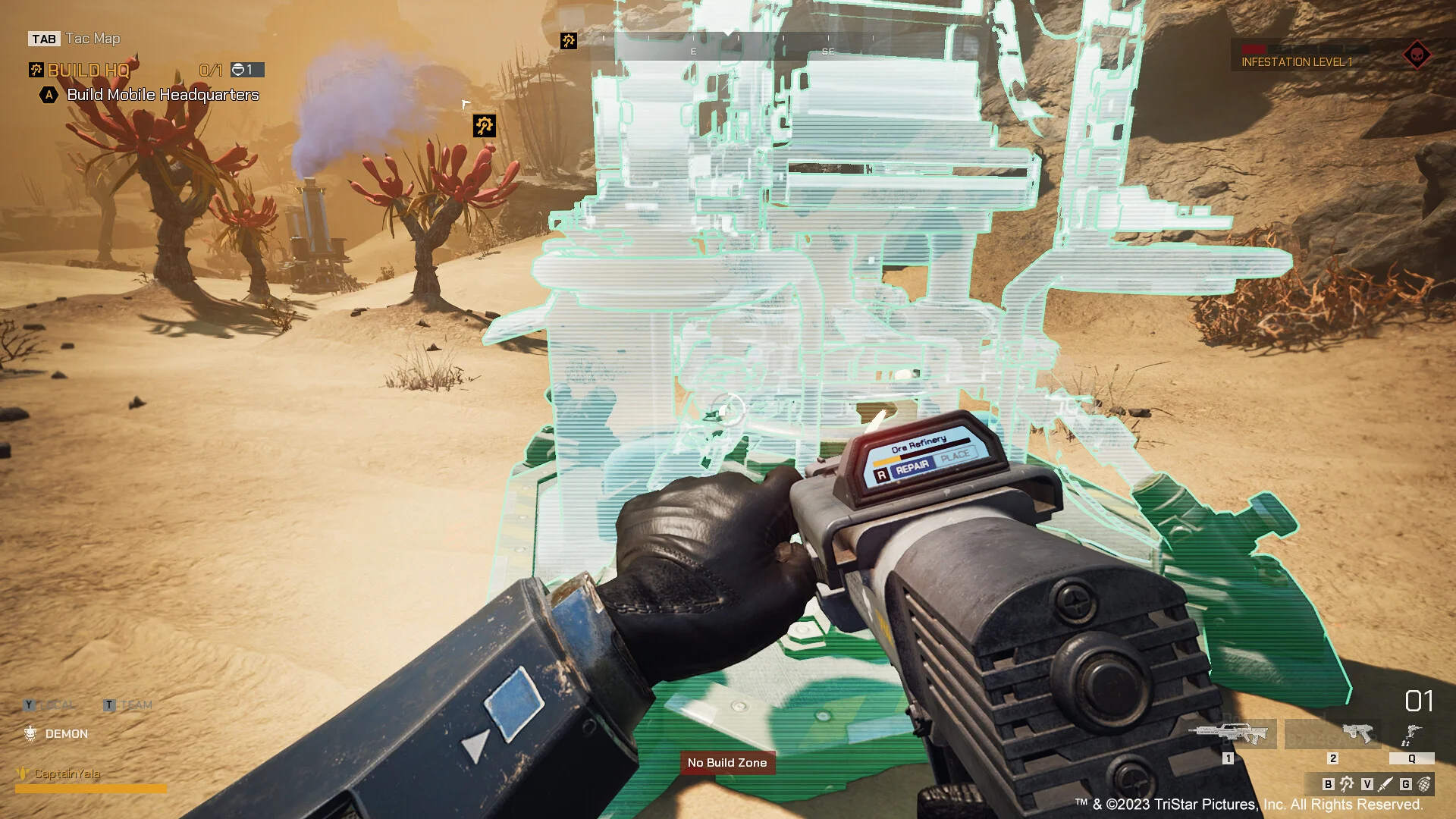 First-person green hologram of a buildable tower with a Repair prompt on a sand field