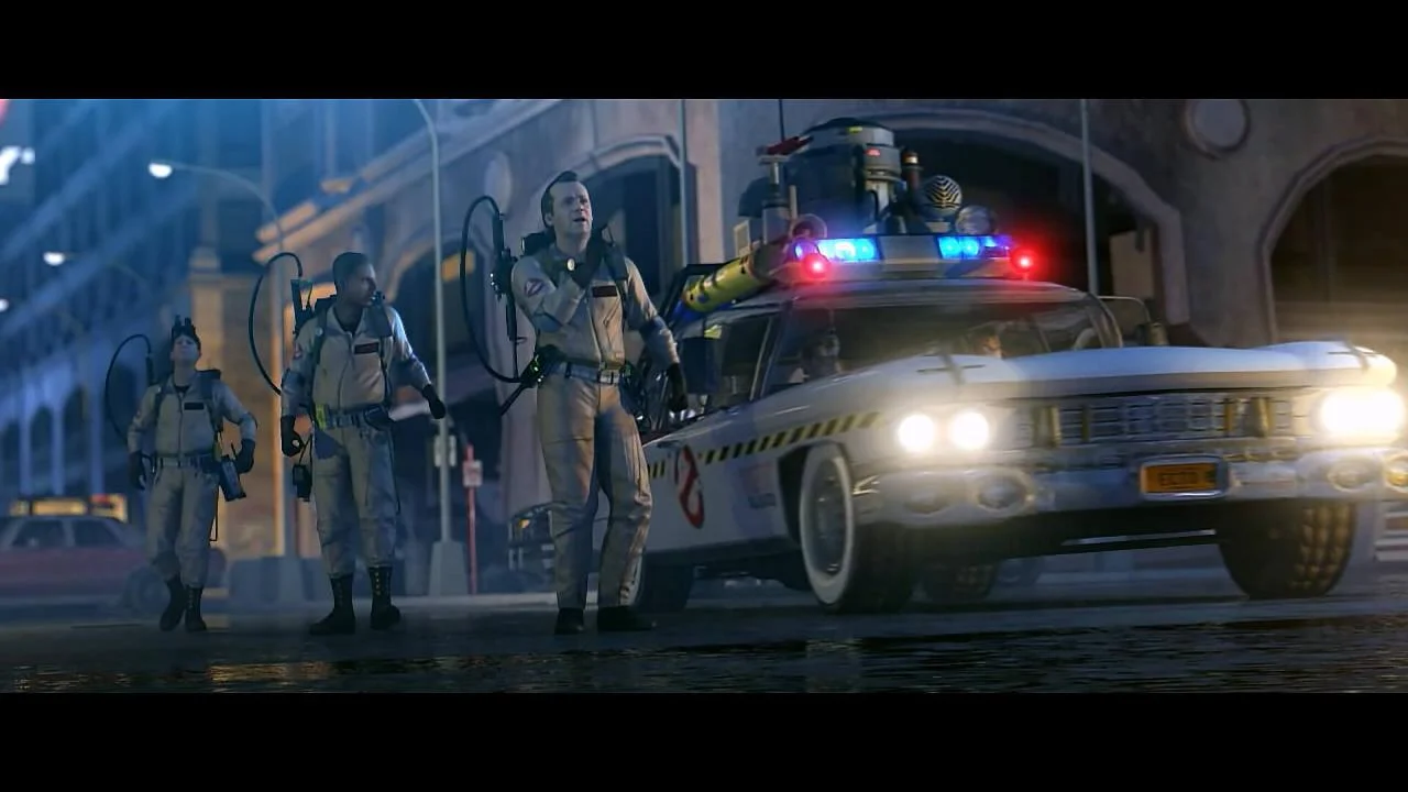 The team stands in front of the Ecto-1 on a city street at night.
