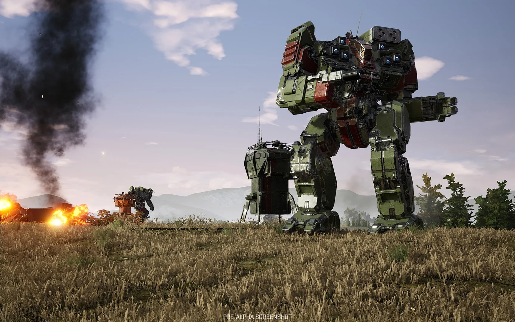 A green-and-red assault mech standing in dry grass with another mech and fire behind it