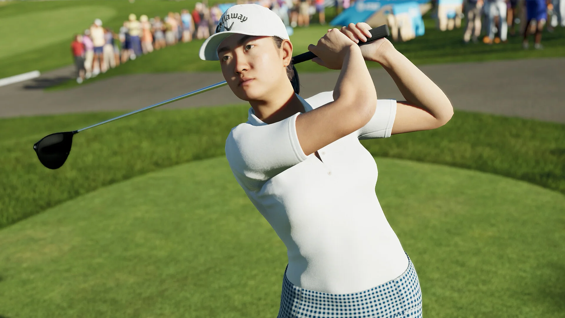 A golfer in a white Callaway cap and checkered skirt mid-swing on a sunlit fairway