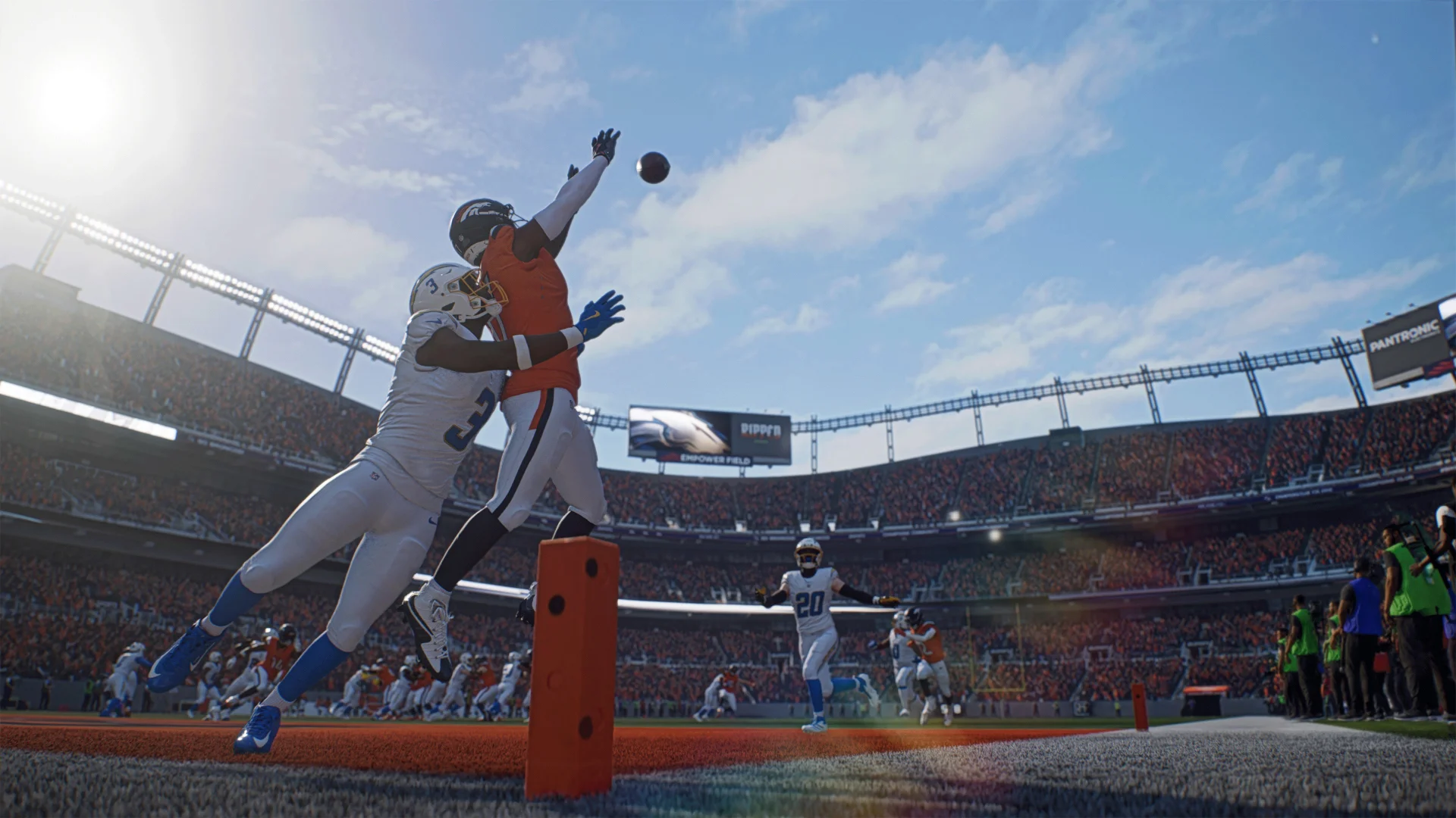 Two players jumping at an orange pylon under a packed sunlit stadium