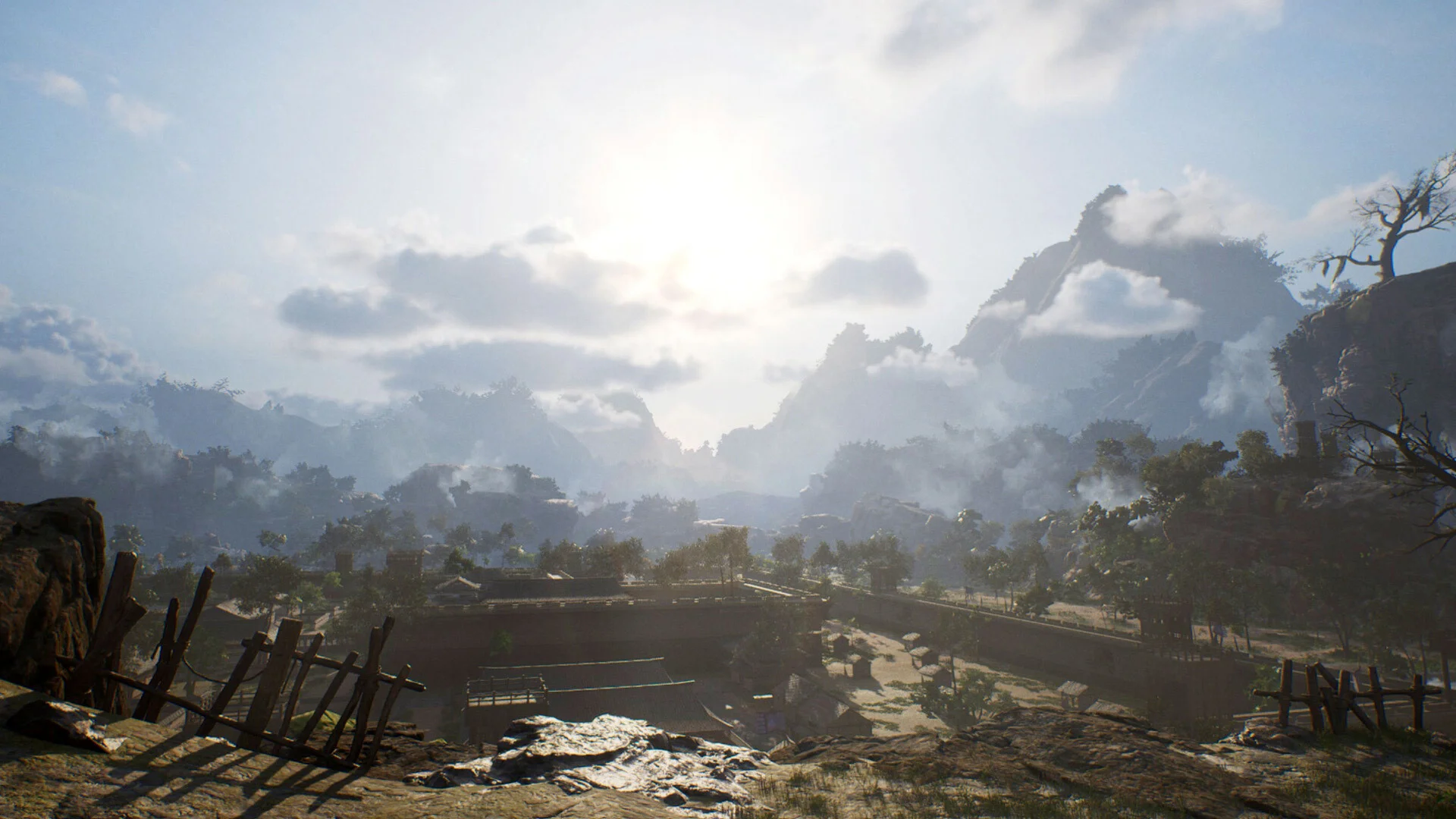Sunlit valley village with wooden fences, mountains and rising smoke
