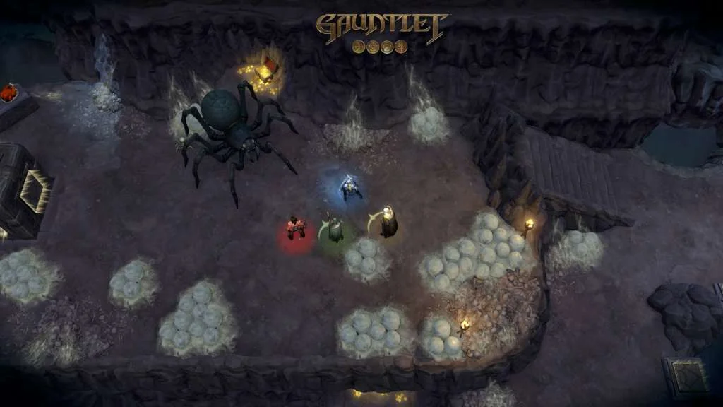 Top-down cave where a giant spider faces four heroes in red, green, blue and gold auras beside egg clusters