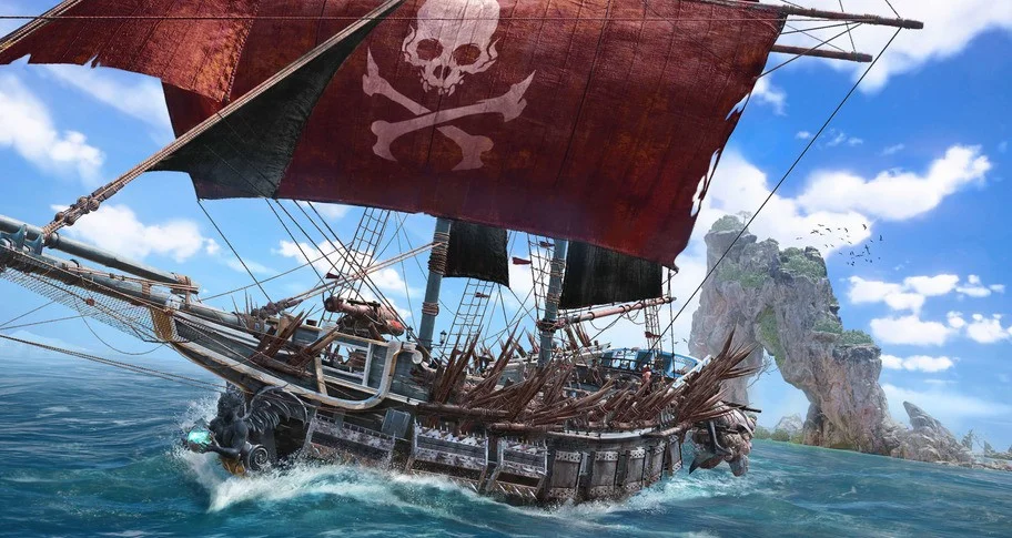 A pirate ship with a red skull sail near a rocky arch.